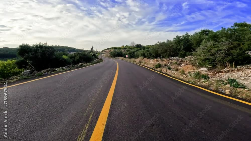 Driving car on mountain asphalt road with yellow markings under blue sky. Perfect road travel scene with scenic travel views. Travel by road in sunny weather, ideal for road trip lovers Driving car on mountain asphalt road with yellow markings under blue sky. Perfect road travel scene with scenic travel views. Travel by road in sunny weather, ideal for road trip lovers