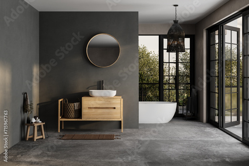 Modern bathroom interior with dark walls, ceramic basin with mirror, bathtub and grey concrete floor. Minimalist black bathroom with modern furniture and big windows, yard. photo