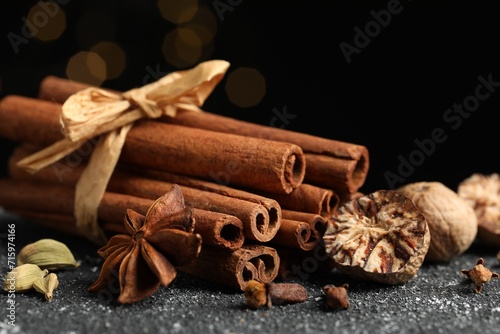 Different aromatic spices on grey textured table against black background, closeup