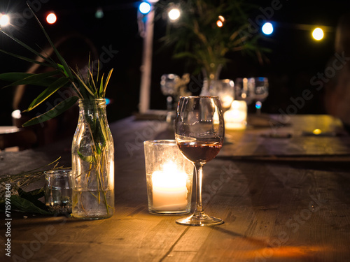 Glass of wine and candle on a wooden table during a party