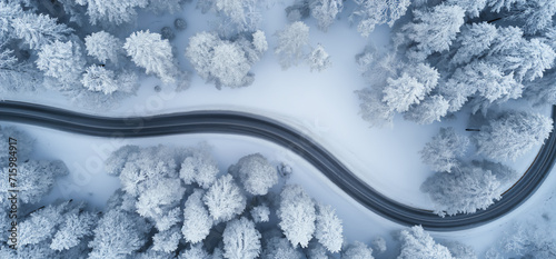 Curvy windy road in snow covered forest, top view, aerial view. 
