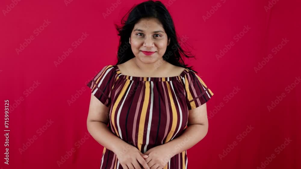 Portrait of a smiling woman with dark hair on a red background wearing a striped top Portrait of a smiling woman with dark hair on a red background wearing a striped top