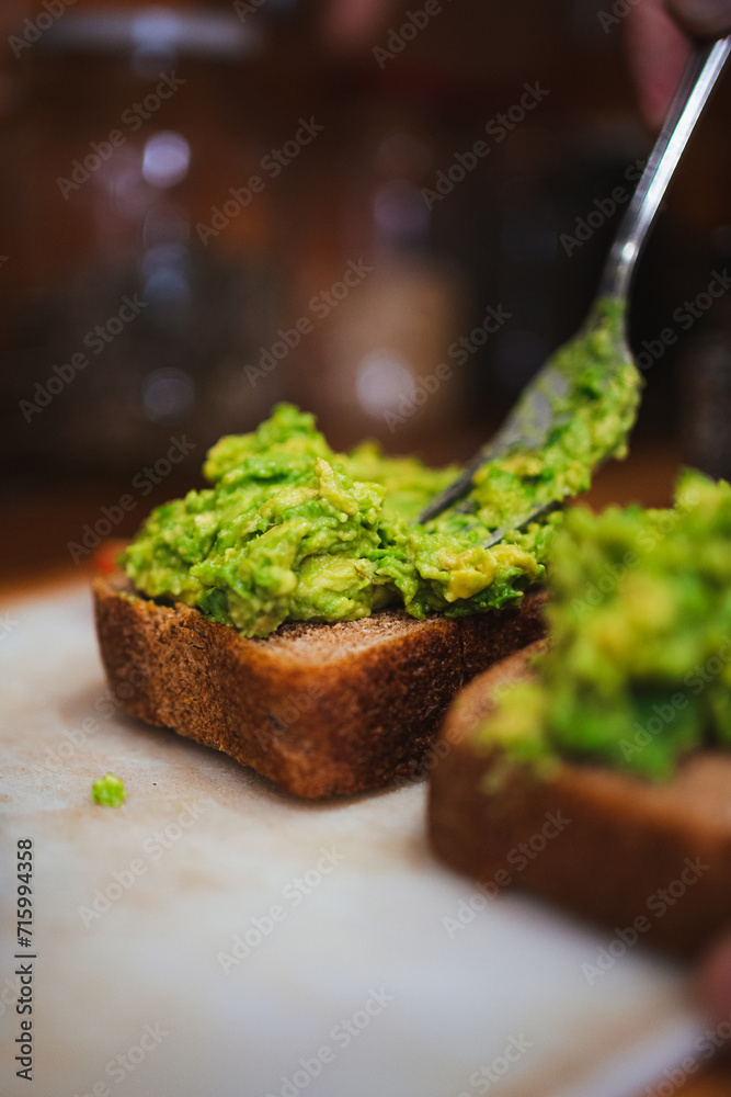 Man mashing avocado with fork on sourdough toasts in a cafeteria in Chile.