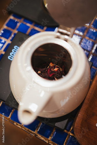 Top view of hibiscus tea leaves inside a teapot being weighted.
