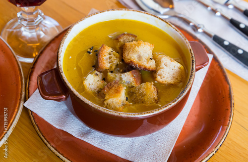 Delicious pureed vegetarian soup served with crispy croutons in clay tureen.. photo