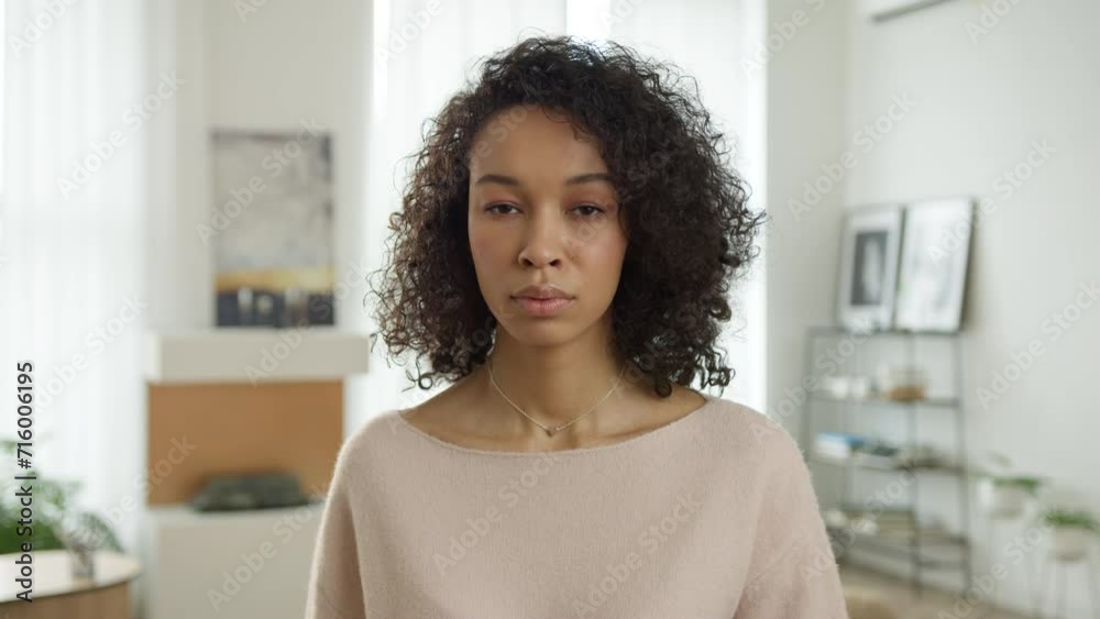 Calm biracial woman looking at camera on motion background. Portrait woman of color in casual sweater posing inside living room. Confident multi ethnic elegant lady standing in modern interior home. Calm biracial woman looking at camera on motion background. Portrait woman of color in casual sweater posing inside living room. Confident multi ethnic elegant lady standing in modern interior home.