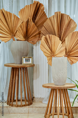 two wooden stools with white porcelain vases and natural leaves decorating