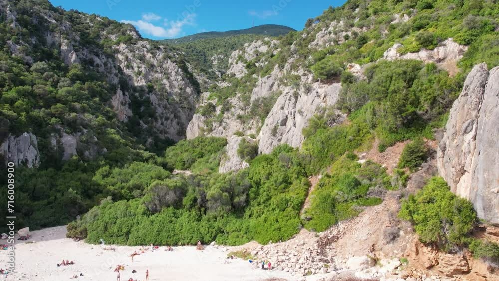 Aerial drone view on white sand Cala Fuili beach of Sardegna. Warm turquoise sea and small beach surrounded with green mountains on the Sardinia island. Aerial drone view on white sand Cala Fuili beach of Sardegna. Warm turquoise sea and small beach surrounded with green mountains on the Sardinia island.