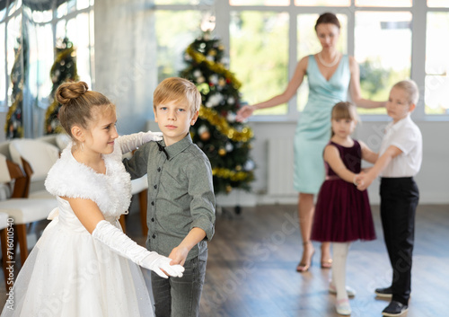 Little children in festive clothes dance the foxtrot dance while celebrating Christmas