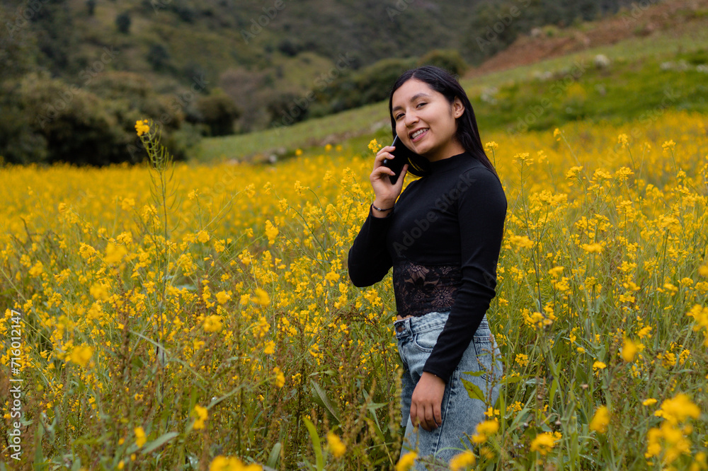 Contrastes florales entre la serenidad de las flores amarillas y la modernidad de un turista alegre con camiseta negra y su celular,comunicación aire libre,tecnologia Contrastes florales entre la serenidad de las flores amarillas y la modernidad de un turista alegre con camiseta negra y su celular,comunicación aire libre,tecnologia
