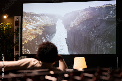 Foto Homeowner chilling on couch in apartment watching nature documentary with breathtaking cinematography on huge TV screen