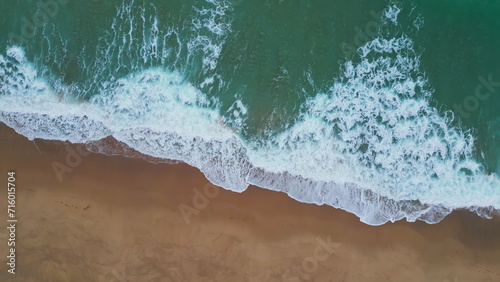 White marine foam washing sand closeup. Aerial turquoise water rolling seashore