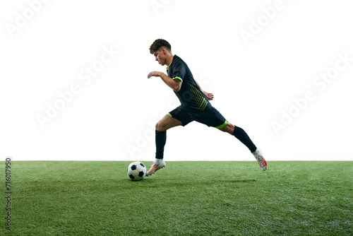 Young man, football player in motion during game, running with ball isolated over white background with grass flooring. Concept of sport, game, competition, championship, active lifestyle © master1305