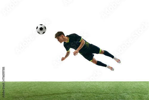 Dynamic image of young man, football player in motion, hitting ball with head isolated over white background with grass flooring. Concept of sport, game, competition, championship, active lifestyle © master1305