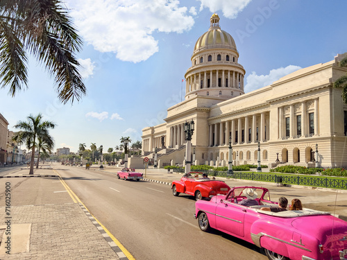 Photography Street view of vintage convertible cars driving in front of El Capitolio