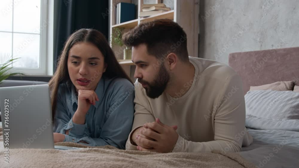 Caucasian couple married wife husband lying on bed family talking discuss shopping online together use laptop internet order young woman man clients looking at computer choosing home goods for bedroom Caucasian couple married wife husband lying on bed family talking discuss shopping online together use laptop internet order young woman man clients looking at computer choosing home goods for bedroom
