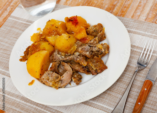 Piquant chopped rabbit stewed in gravy with potatoes seasoned with dried herbs for dinner..