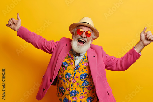 Portrait of a happy senior man in hat and sunglasses over yellow background