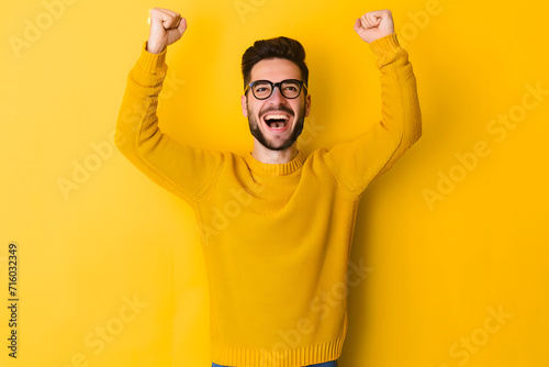 Portrait of a happy young man celebrating success isolated over yellow background photo