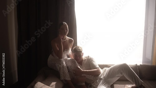 The bride and groom in pathetic poses are sitting on the bed