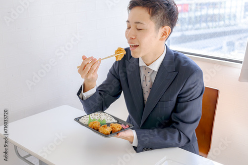 弁当を食べるスーツの男性