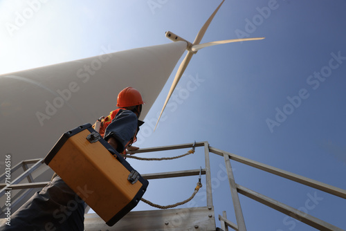 Windmill worker with safety harness and PPE working under wind turbine 