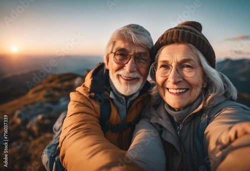 Happy senior couple taking selfie on top of mountain at sunset