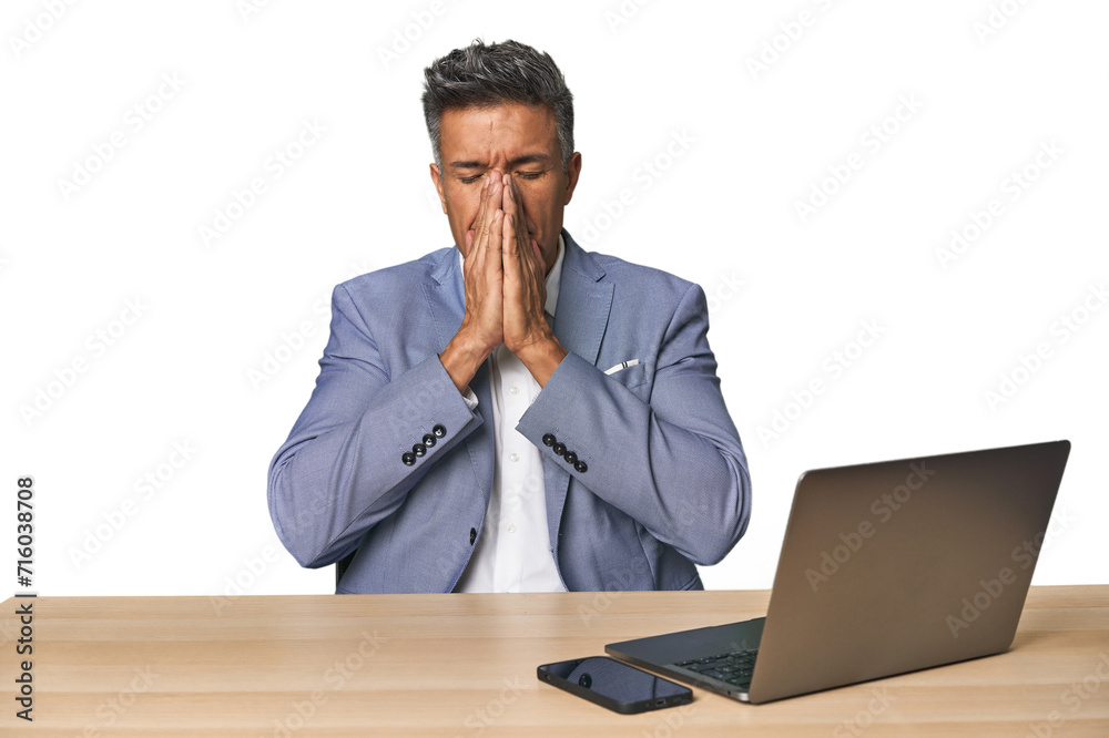 Elegant businessman at desk with laptop holding hands in pray near mouth, feels confident. Elegant businessman at desk with laptop holding hands in pray near mouth, feels confident.