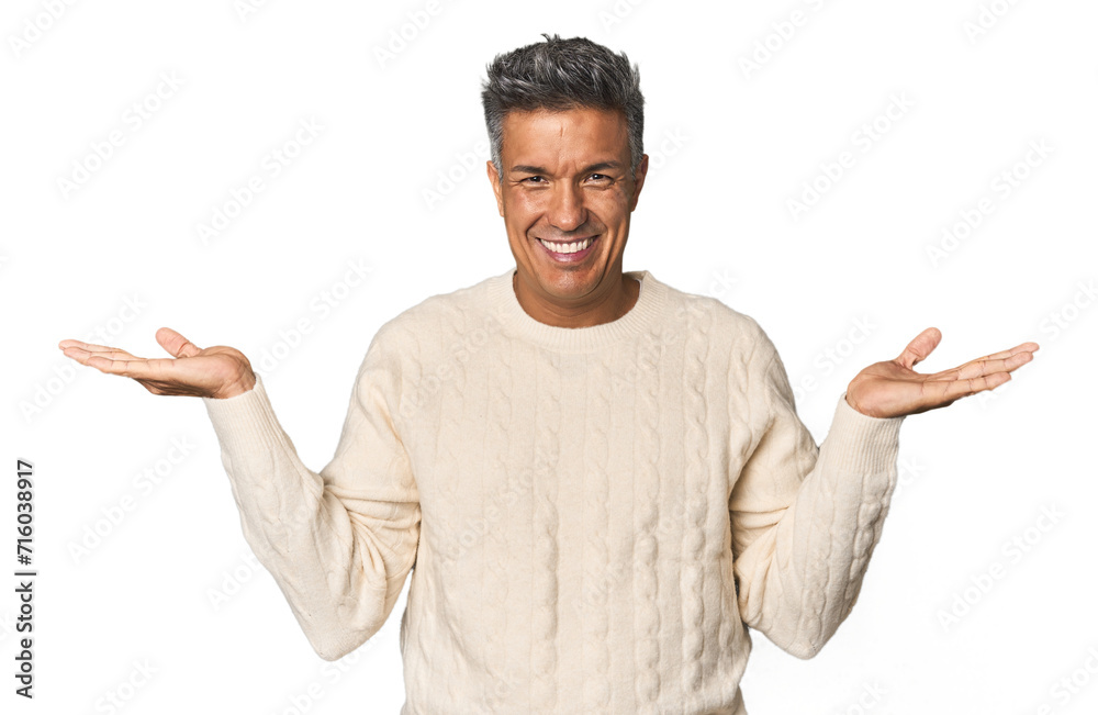 Middle-aged Latino man makes scale with arms, feels happy and confident. Middle-aged Latino man makes scale with arms, feels happy and confident.