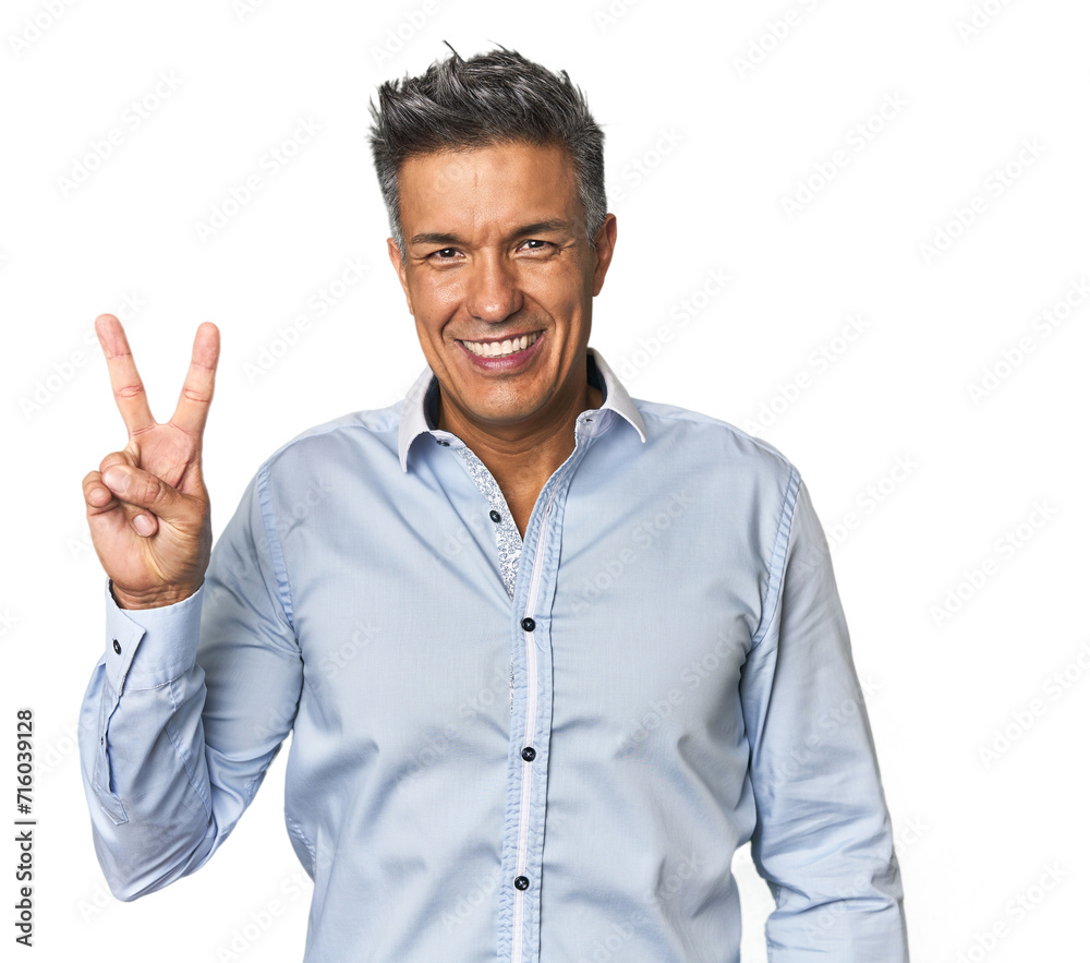 Middle-aged Latino man joyful and carefree showing a peace symbol with fingers. Middle-aged Latino man joyful and carefree showing a peace symbol with fingers.