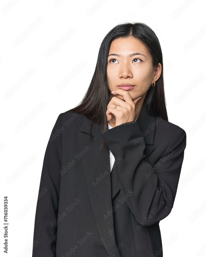 Young Chinese woman in business suit looking sideways with doubtful and skeptical expression. Young Chinese woman in business suit looking sideways with doubtful and skeptical expression.