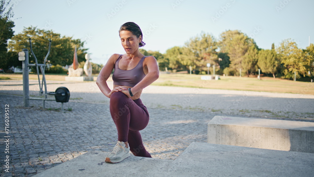 Obraz premium Flexible woman stretching legs at urban gym. Confident sportswoman warming up