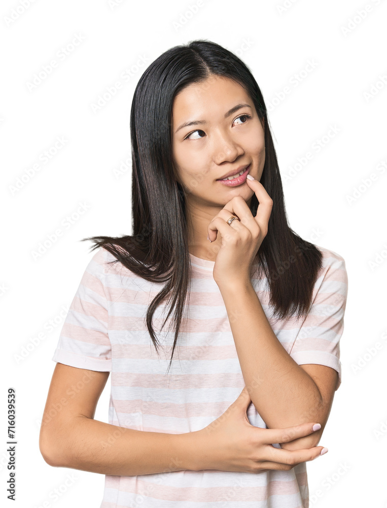 Young Chinese woman in studio setting relaxed thinking about something looking at a copy space. Young Chinese woman in studio setting relaxed thinking about something looking at a copy space.
