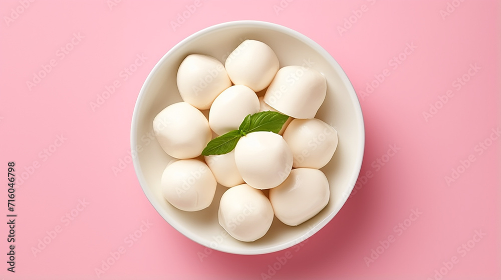 Mozzarella cheese balls in bowl on light pink background, top view	
