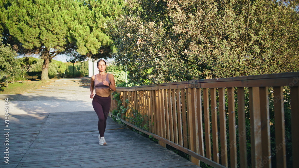 Fit lady running cardio workout at summer city. Motivated woman runner training Fit lady running cardio workout at summer city. Motivated woman runner training