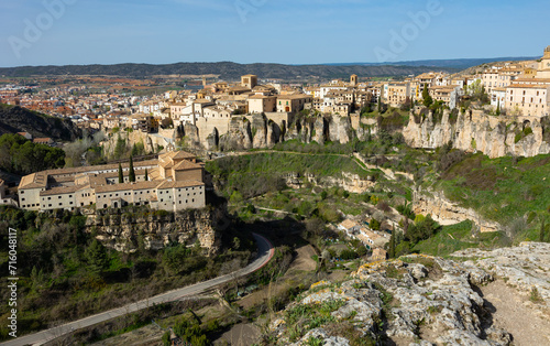 Scenic view of ancient Spanish city of Cuenca on sunny spring day overlooking convent of San Pablo located on rocky ledge above gorge with Huecar river in front of Hanging Houses.. photo