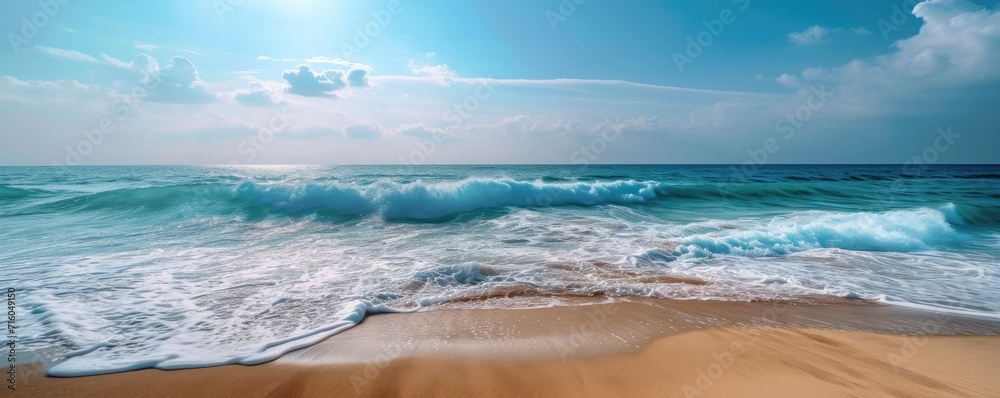 Calm beach landscape with golden sand, tranquil waves and a blue sky