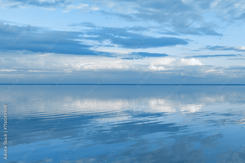 Beautiful white blue clouds over lake, symmetric sky background, cloudscape on lake Ik, Russia. Nature abstract, cloudy sky reflected on water, calm windless weather, natural environment