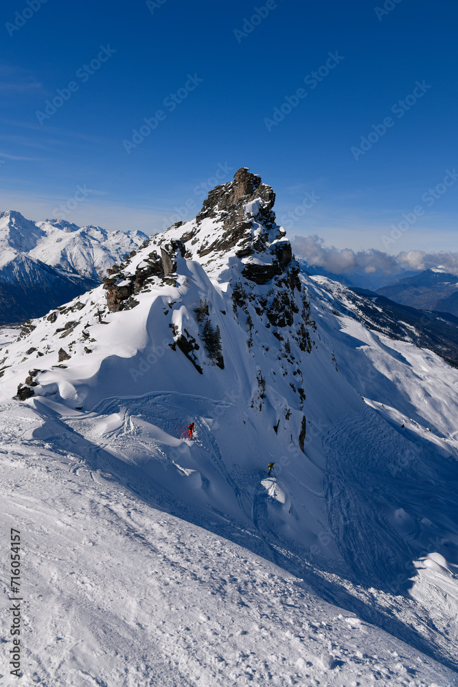Two advanced skiers doing free ride at the off piste area at the Meribel ski resort in France, breathtaking landscape view around.