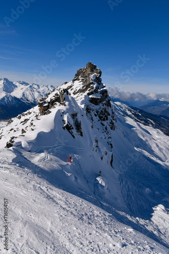 Two advanced skiers doing free ride at the off piste area at the Meribel ski resort in France, breathtaking landscape view around.