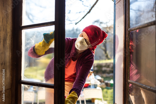 Adult Caucasian Woman Cleaning Old House Windows With Face Mask During Renovation Works