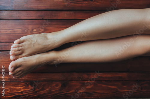 Two female feet on a brown wooden floor background close up. Foot hygiene concept.