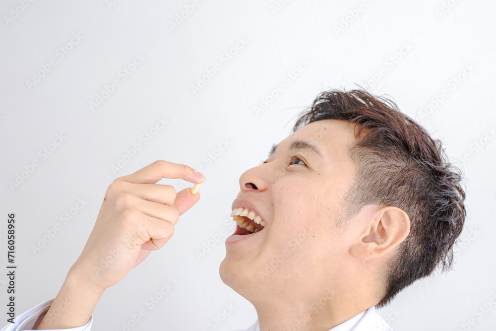 薬を飲む白衣の男性 薬を飲む白衣の男性