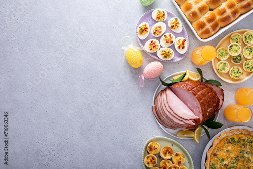 Easter brunch on large table with spiral sliced ham, quiche, deviled eggs and hot cross buns photo