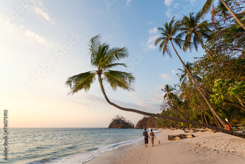 Couple of tourists walking on exotic beach at sunset, Costa Rica photo