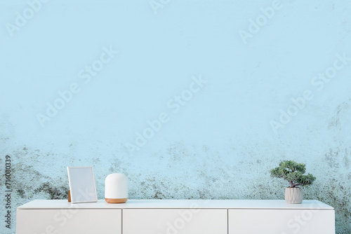 Schilderij op canvas Modern chest of drawers with houseplant and blank picture near blue wall in room