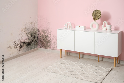 Stylish rug and white sideboard with decor near pink wall photo