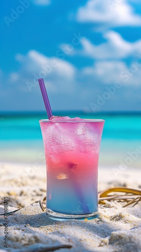 A glass of ice-cold cocktail in pastel colors on a hot summer day at the beach. Refreshing iced cocktail to enjoy a relaxing moment by the sea.