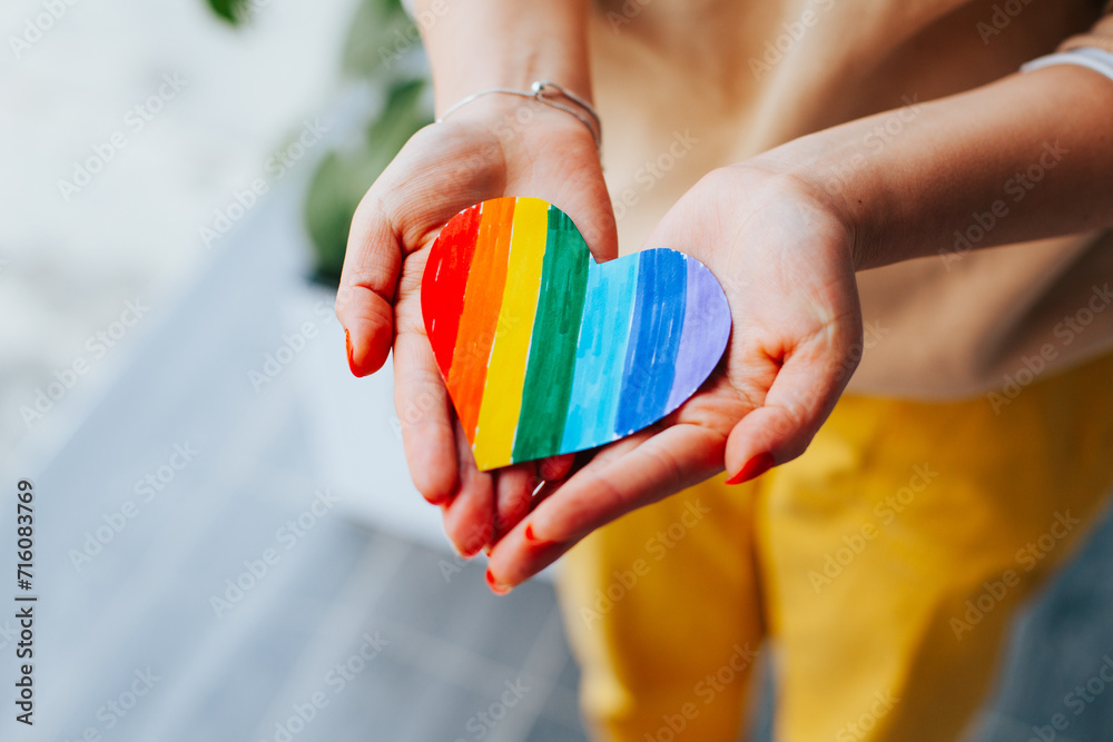 Photograph of woman's hands holding a hand drawn LGBTQ+ heart. Concept of people and lifestyles.
