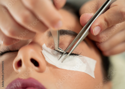 Beautiful girl getting silk eyelashes in salon, closeup 